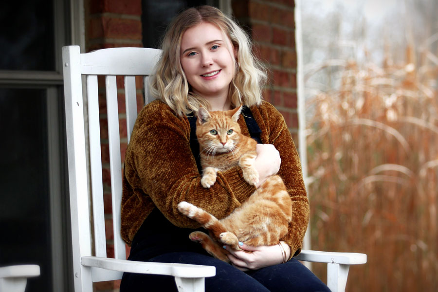 woman sat outdoors holding ginger cat